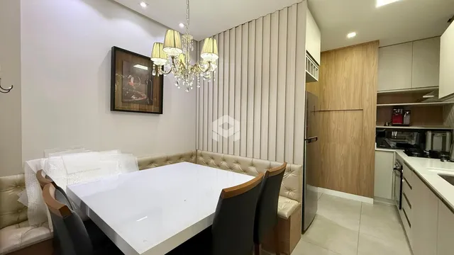 Ambiente de jantar com mesa branca e estofados em uma sala de estar.