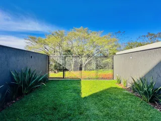 Vista externa de um quintal com gramado e cerca de metal.