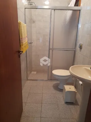 Foto de um banheiro com box de vidro e piso de cerâmica.