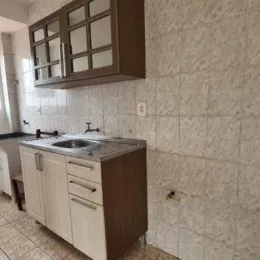 Vista parcial de armários e bancada com pia em um ambiente interno.