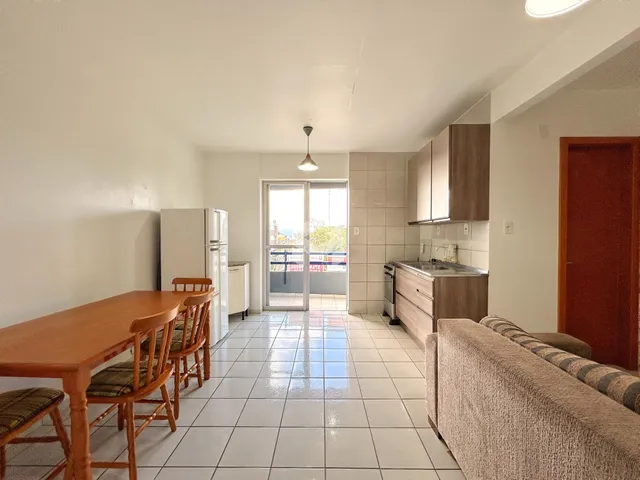 Vista de uma sala de jantar e cozinha com piso de cerâmica clara.