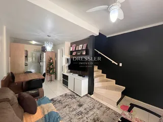 Ambiente interno de sala de estar e jantar com piso claro e paredes escuras.