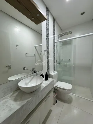 Foto de um banheiro com bancada de mármore e box de vidro.