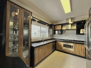 Vista da cozinha com armários de madeira e bancadas escuras.