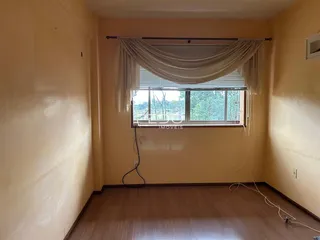 Imagem de uma sala de estar com paredes amarelas e piso de madeira.