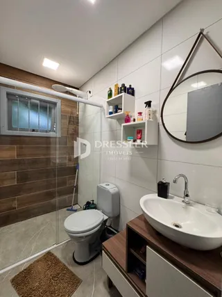 Foto de um banheiro com box de vidro e louças sanitárias.