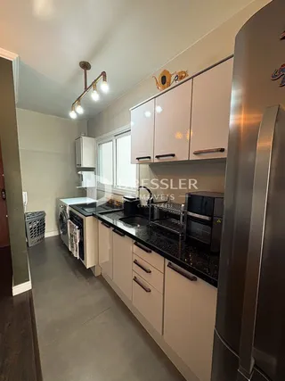 Vista da cozinha moderna com armários brancos e bancadas escuras.