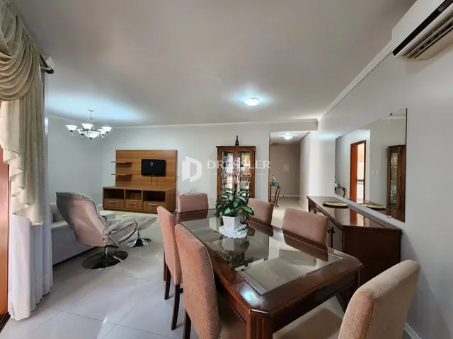 Sala de estar com mesa de jantar e móveis de madeira em um imóvel no Brasil.