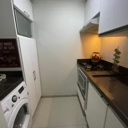 Uma foto interna de uma cozinha com armários brancos e bancada escura.
