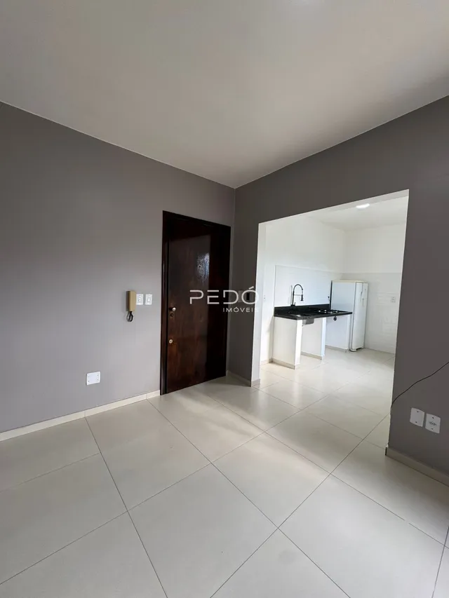 Interior de um corredor com porta de madeira escura e piso de cerâmica clara.