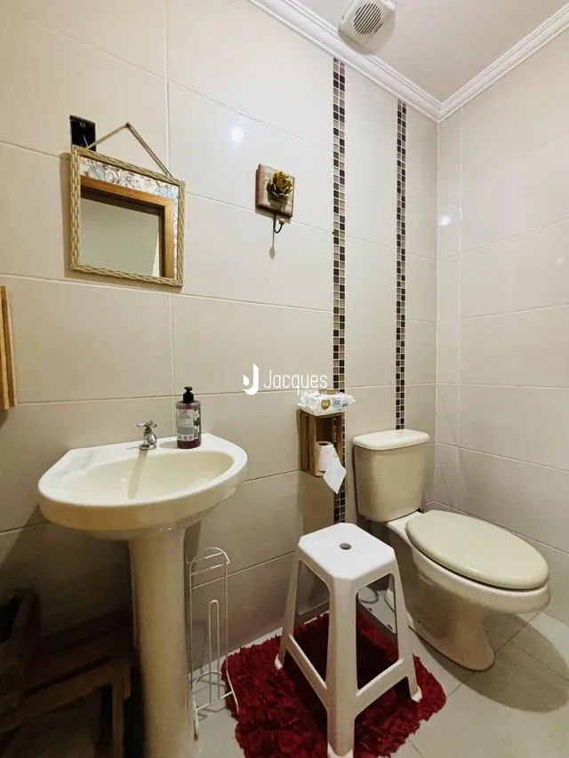 Interior de um banheiro com pia e vaso sanitário em cerâmica.
