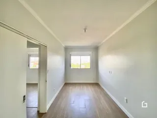 Corredor interno de uma residência com piso de madeira clara.