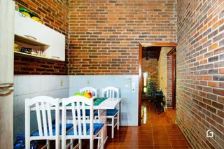 Uma sala de jantar com paredes de tijolo aparente e móveis brancos.