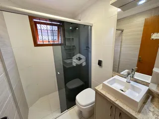 Banheiro com box de vidro e pia de mármore.