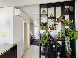 Hall de entrada com estante escura e decoração verde.