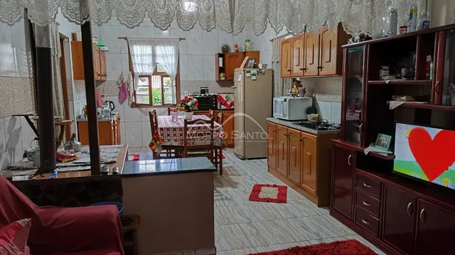 Cozinha com armários de madeira e mesa de jantar em ambiente interno.