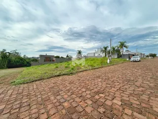 Vista externa de uma propriedade com terreno gramado e pavimentação de tijolos.