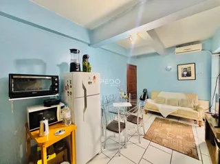 Sala de estar com mesa de jantar e geladeira branca em um apartamento.