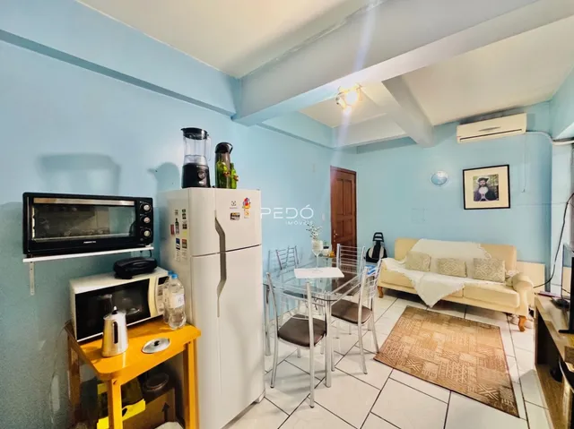 Sala de estar com mesa de jantar e geladeira branca em um apartamento.
