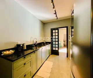 Vista da cozinha com armários verdes e bancadas escuras.