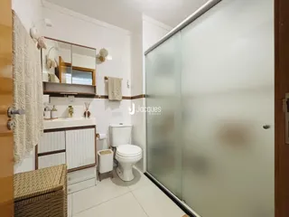 Foto de um banheiro com piso branco e box de vidro transparente.