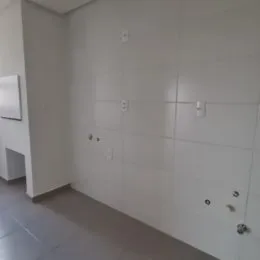 Vista interna de um corredor com paredes brancas e piso claro.