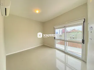 Ambiente interno de uma sala com piso claro e porta de vidro que dá para a vista externa.