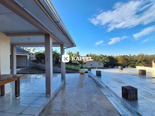 Vista externa pavimentada mostrando uma área de lazer com paisagem ao fundo.