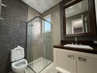 Banheiro com box de vidro e revestimento de cerâmica.
