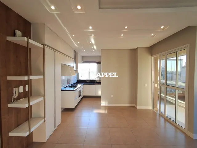 Foto do interior de uma sala de estar moderna com cozinha e porta de vidro.