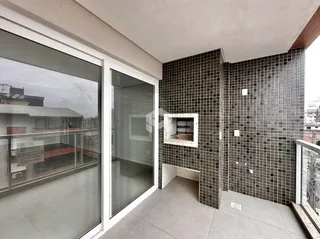 Vista de uma área externa com parede revestida de azulejos escuros e portas de vidro.