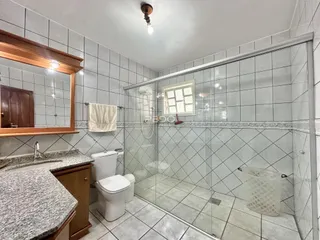 Banheiro com revestimento cerâmico e box de vidro.