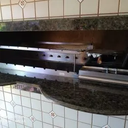 Detalhe da bancada e revestimento da cozinha com granito escuro e azulejos brancos.