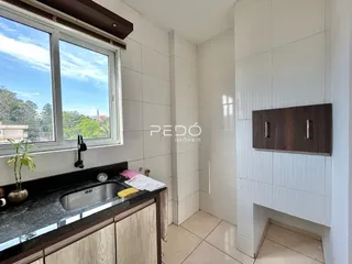 Vista de uma cozinha com janela e bancada escura.
