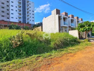 Vista externa de um imóvel com vegetação alta no primeiro plano.