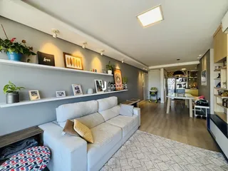 Sala de estar ampla com sofá branco e decoração de parede em um imóvel no Brasil.