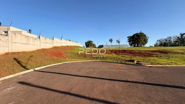 Vista da propriedade com muro e terreno inclinado.