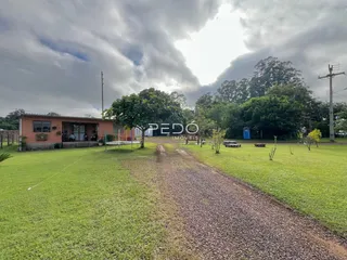Vista externa de uma propriedade com gramado e caminho de terra.