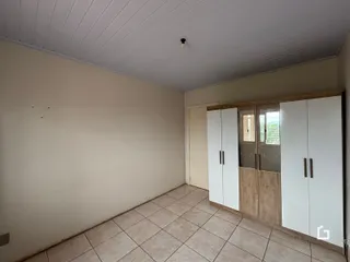 Quarto interno com piso de cerâmica e armários em madeira.