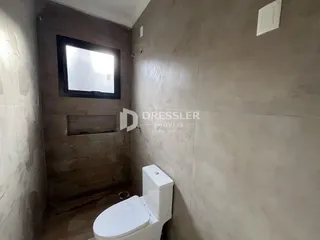 Foto de um banheiro interno com vaso sanitário e parede de madeira.