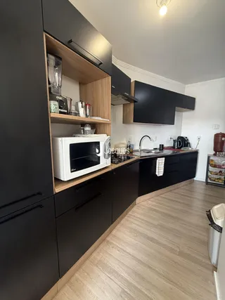 Foto de uma cozinha moderna com armários escuros e bancadas de madeira clara.