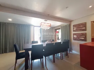 Uma sala de jantar com mesa de madeira e cadeiras escuras.