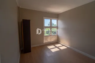 Quarto com piso de madeira e grande janela.