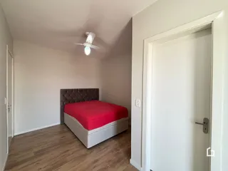 Quarto com cama e piso de madeira clara.