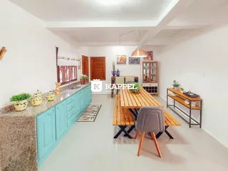 Cozinha com armários azuis e mesa de madeira em ambiente claro.