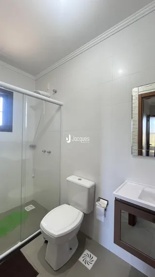 Foto de um banheiro interno com box de vidro e vaso sanitário branco.