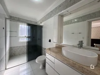 Banheiro com bancada e box de vidro.