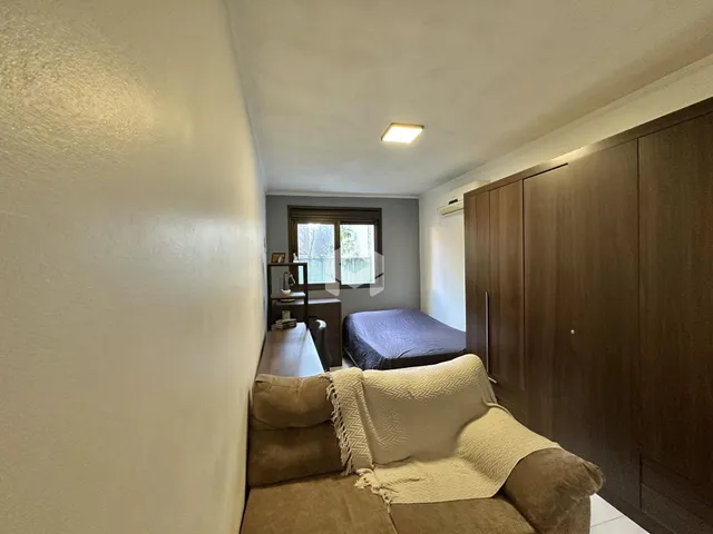 Quarto com armários em madeira e sofá na sala de estar.