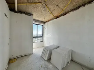 Interior de um cômodo com teto de concreto aparente e paredes brancas.
