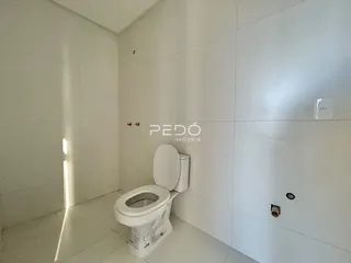 Foto de um banheiro com revestimento branco e piso claro.